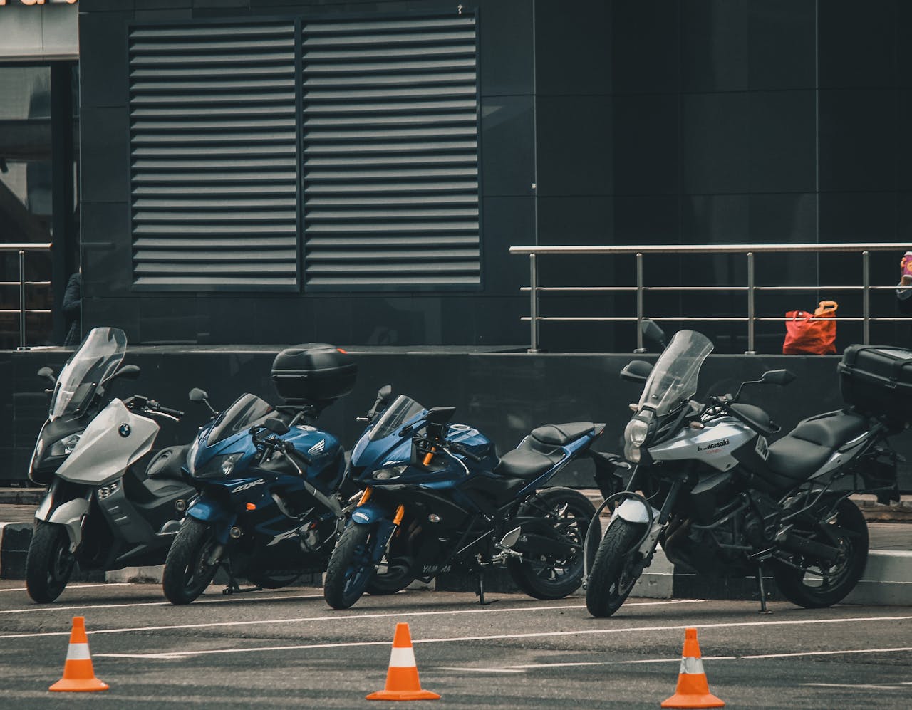Parked motorcycles lined up in a city, an urban view with modern architecture in the background.